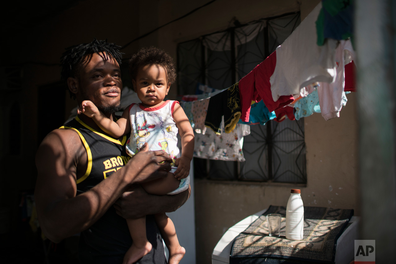  In this May 27, 2016 photo, Popole Misenga, a refugee and judo athlete from the Democratic Republic of Congo who hopes to make the cut for the first Olympic team of refugee athletes, holds his one-year-old son Elias at their home in Rio de Janeiro, 