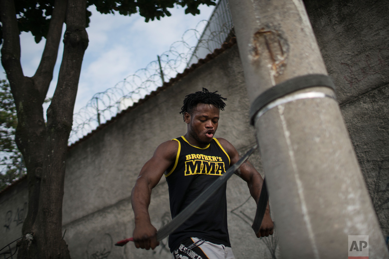  In this May 27, 2016 photo, Popole Misenga, a refugee and judo athlete from the Democratic Republic of Congo, uses a judo black belt attached to a street light pole to trains near his home in Rio de Janeiro, Brazil, in hopes of making the first Olym