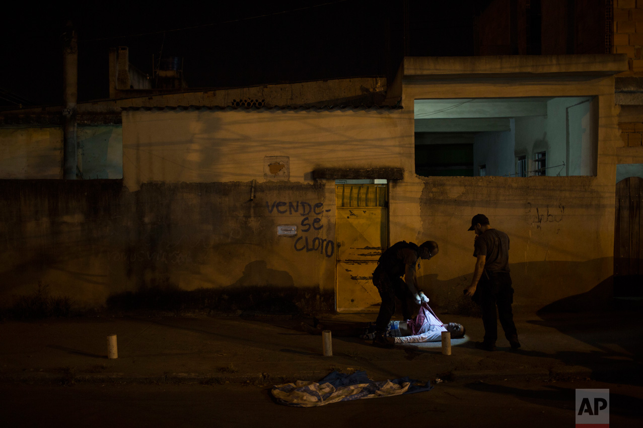  In this July 16, 2016 photo, police responding to a call find the body of a young black man in the middle of a residential street in Caxias, greater Rio de Janeiro, Brazil. Rio's ambitious security push to bring crime down and seize control of certa