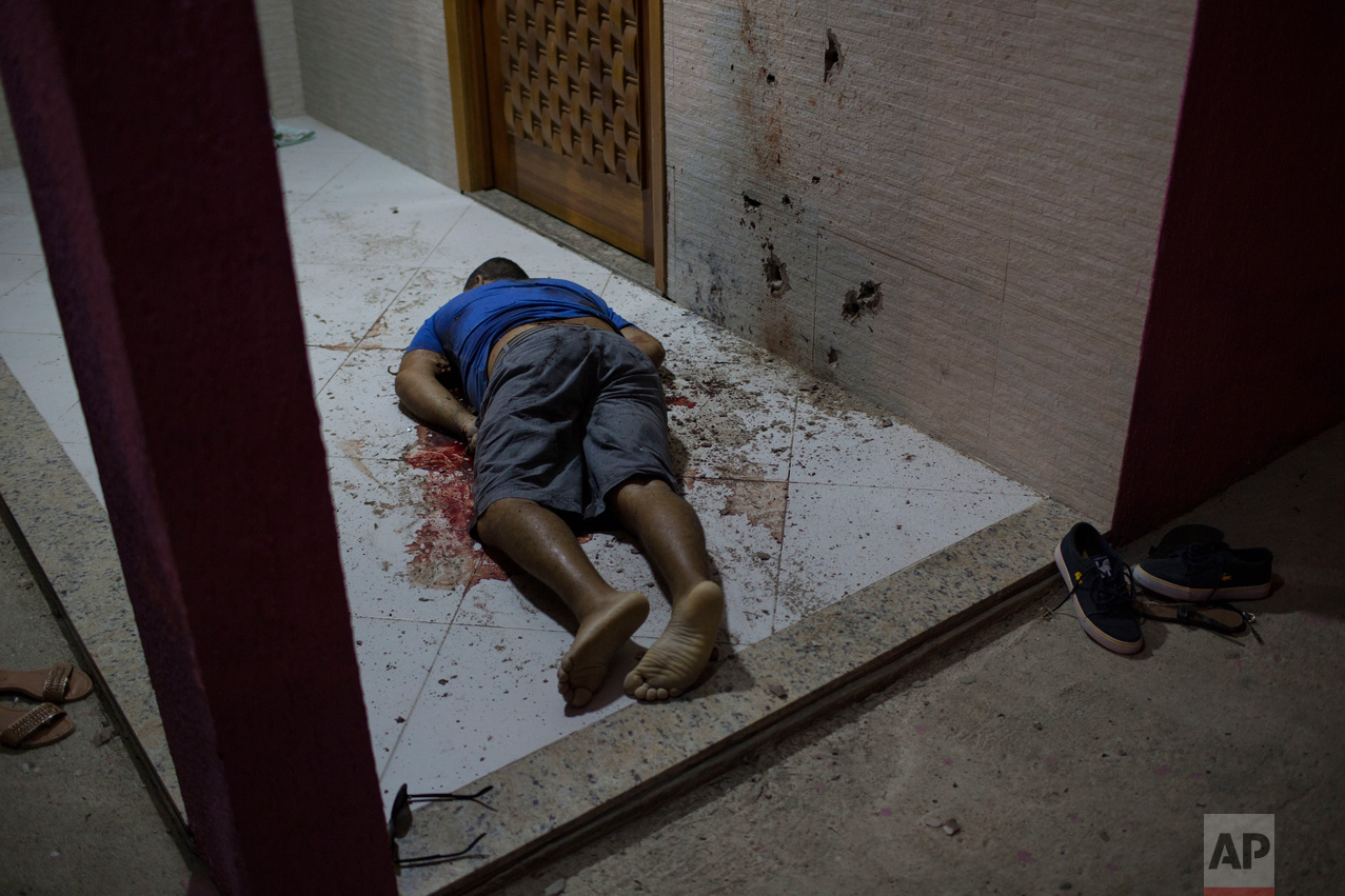  This July 13, 2016 photo shows the body of a man who was taken from the inside of his home and shot dead at the entrance of his home in Nova Iguacu, greater Rio de Janeiro, Brazil. Scenes of impunity and violence play out daily in many of Rio's hund