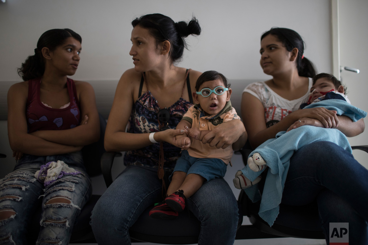  In this Sept. 27, 2016 photo, babies born with  microcephaly Alexandro Julio, center, and Pedro Henrique, wait for their physical therapy session at the UPAE hospital in Caruaru, Pernambuco state, Brazil. A year after a spike in the number of newbor