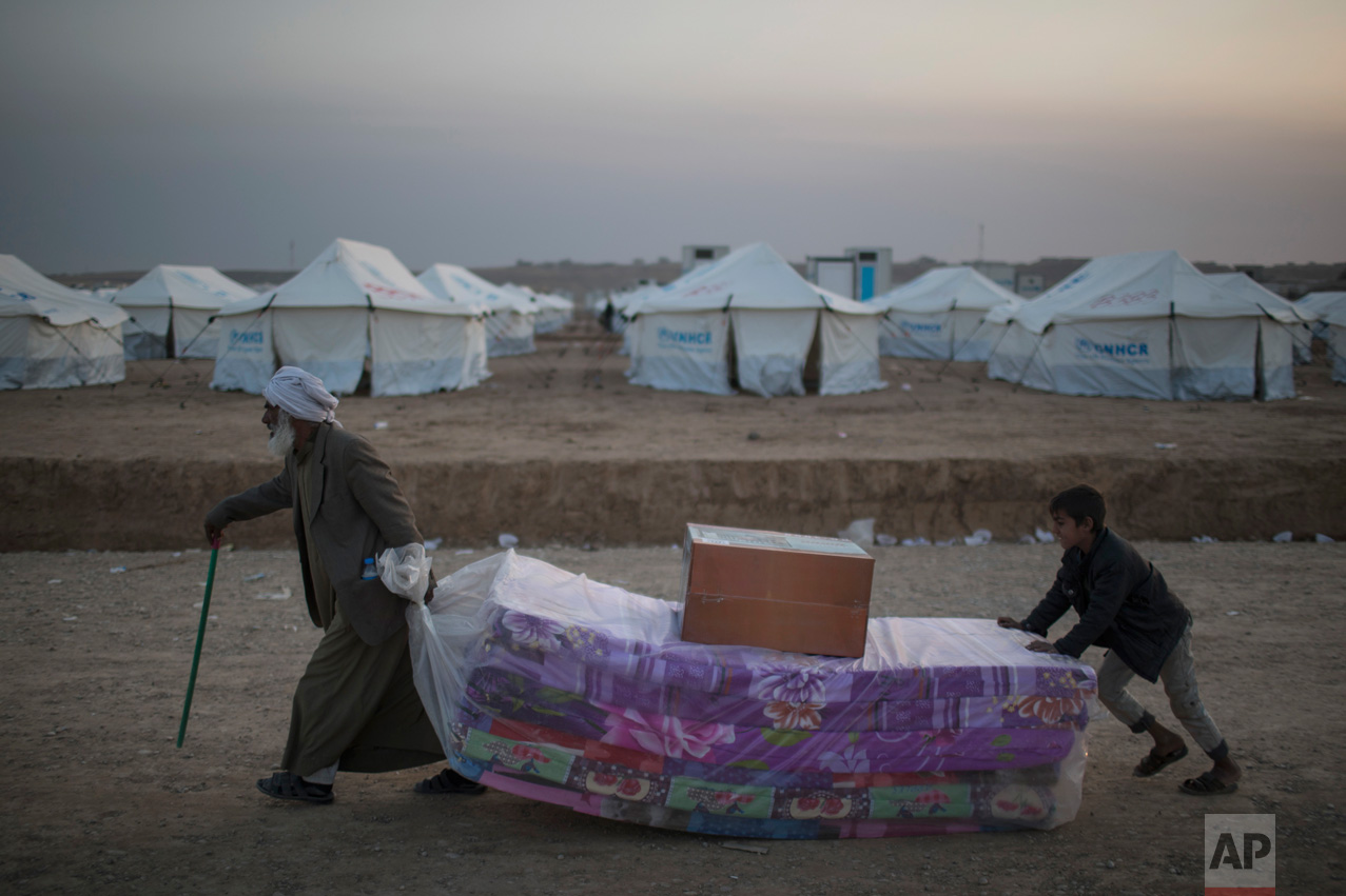  Iraqis displaced by fighting in Mosul carry mattresses at a camp for internally displaced people in Hassan Sham, Iraq, on Tuesday, Nov. 8, 2016. The United Nations says over 34,000 people have been displaced from Mosul, with about three quarters set