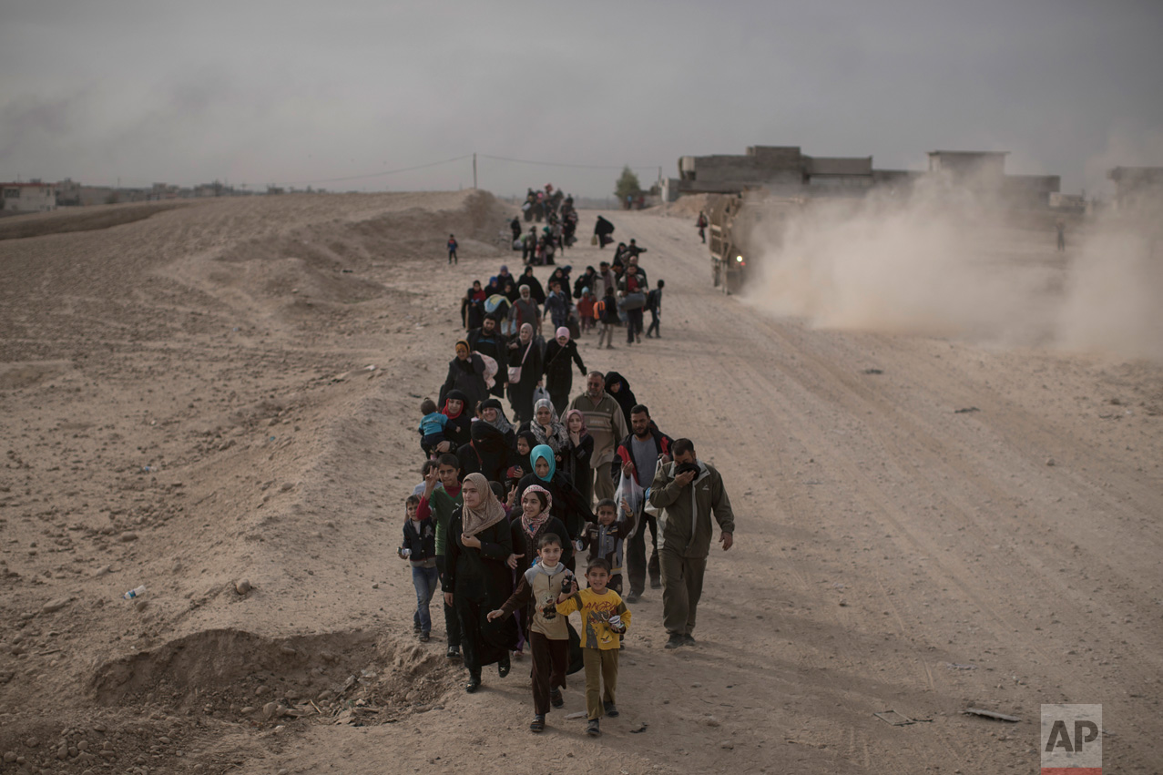  In this Nov. 15, 2016 photo, internally displaced people flee fighting between Iraqi forces and Islamic State militants on a road in eastern Mosul, Iraq. Six weeks into the battle for Mosul, the Iraqi government's 50,000-strong expedition is a long 