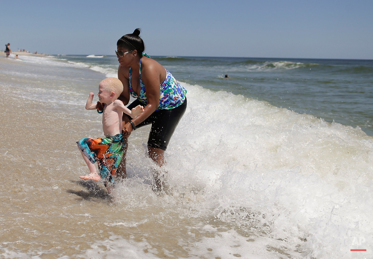  Global Medical Relief Fund assistant Monica Watson, right, helps Baraka Lusambo, 5, dart away from an approaching wave in Long Beach Island, N.J. on Wednesday, July 22, 2015. One out of every 1,400 citizens in Tanzania has albinism. Baraka was attac