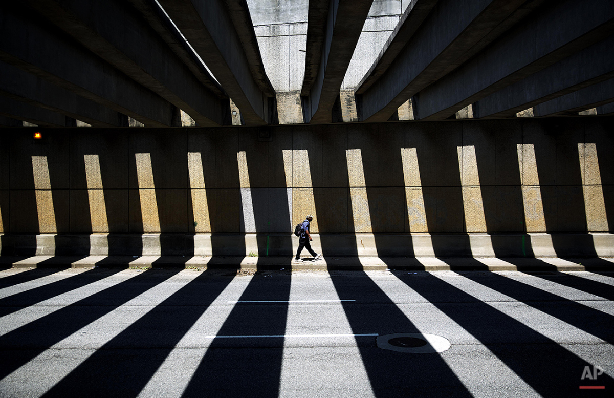  A pedestrian walks through a downtown underpass as the midday sun casts shadows from overhead beams, Thursday, Aug. 7, 2014, in Atlanta. (AP Photo/David Goldman) 