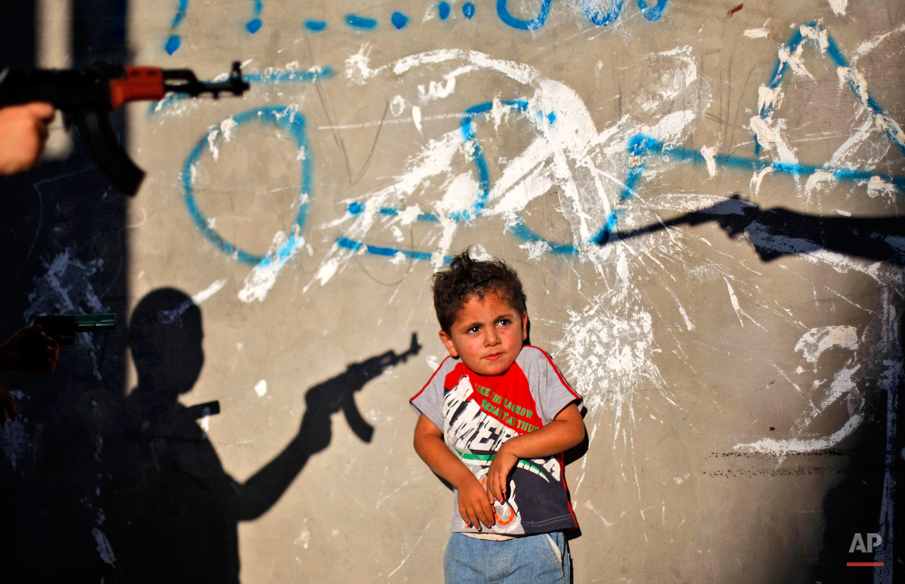 A Palestinian boy reacts as youths frighten him by pointing their toy guns at him, in an alley in the West Bank refugee camp of Al-Amari in Ramallah, Tuesday, June. 16, 2009. (AP Photo/Muhammed Muheisen) 