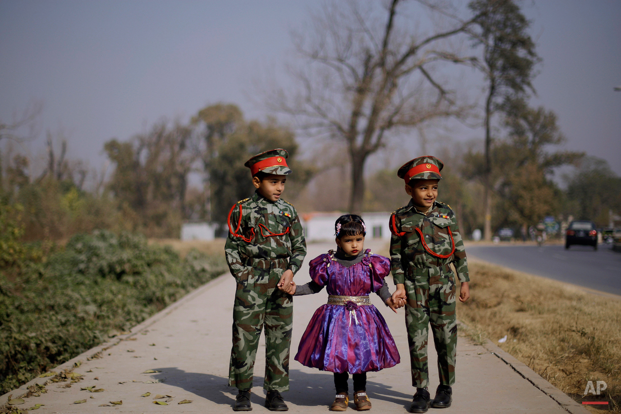  Pakistani Mamouna Qamar, 4, center, looks on while holding her brothers hands, Shazaib, 6, right, and Zaman, 7, as they wait for their parent, unseen, crossing a street in a neighborhood in Islamabad, Pakistan, Friday, Dec. 24, 2010. (AP Photo/Muham