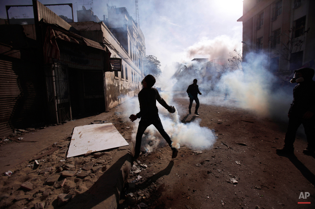  An Egyptian protestor throws away a tear gas canister fired by security forces during clashes near the Interior Ministry in Cairo, Egypt, Friday, Feb. 3, 2012. A volunteer doctor says police and protesters angry over a deadly soccer riot have clashe