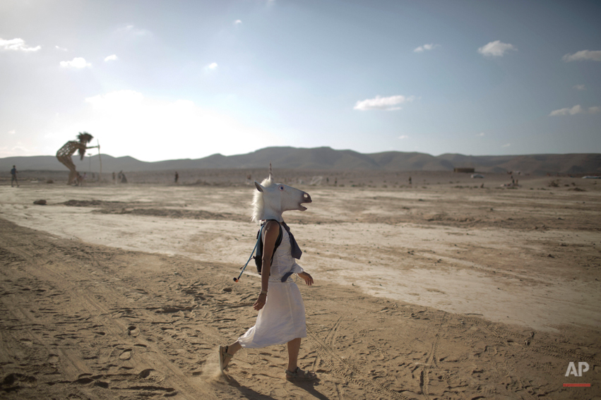  In this photo taken Friday, June 6, 2014, An Israeli woman wears a unicorn mask as she walks in the playa during Israelís first Midburn festival, modeled after the popular Burning Man festival held annually in the Black Rock Desert of Nevada, in the