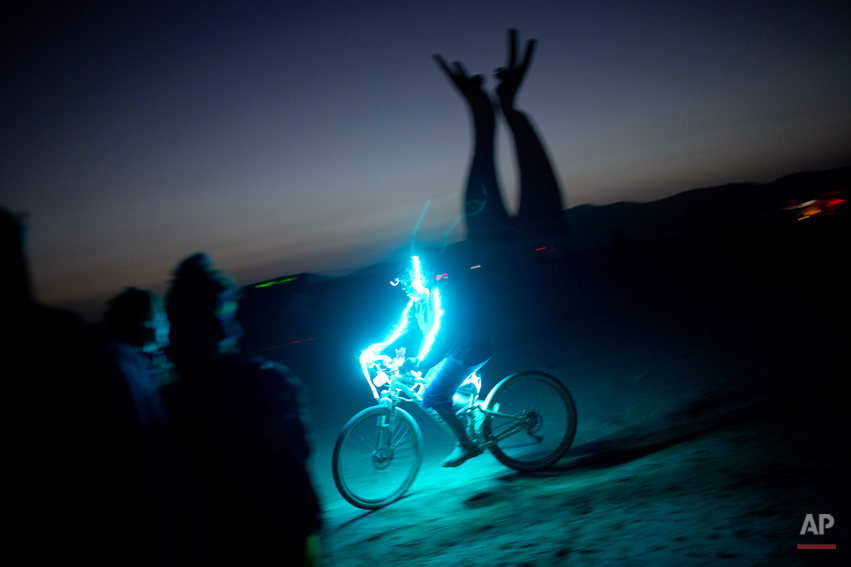  In this photo taken Thursday, June 5, 2014, An Israeli man rides a bicycle as the sun goes down during Israelís first Midburn festival, modeled after the popular Burning Man festival held annually in the Black Rock Desert of Nevada, in the desert ne