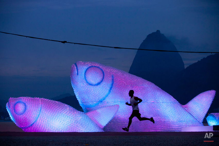  A man runs on Botafogo beach near a huge sculpture made from plastic bottles, backdropped by a silhouette of Sugarloaf mountain in Rio de Janeiro, Brazil,  in the early morning hours of Wednesday, June  20, 2012. The city is host to the United Natio