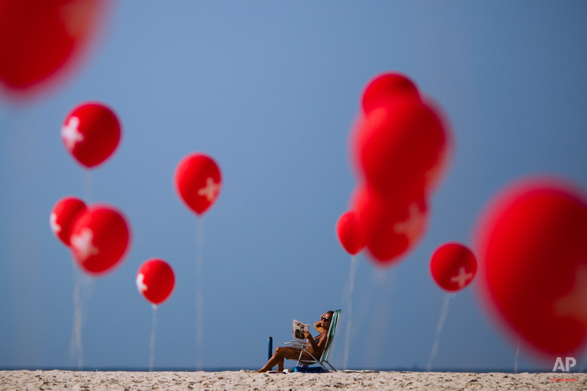  A woman sunbathes next to a demonstration organized by firefighters demanding a wage increase, on Copacabana beach in Rio de Janeiro, Brazil, Sunday June 12, 2011. Organizers brought 439 red balloons representing the number of firemen who were arres