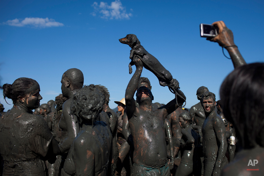  A man covered in mud holds up his mud covered dog as another reveler takes a picture during the "Bloco da Lama" or "Mud Block" carnival parade in Parati, Brazil, Saturday Feb. 18, 2012. (AP Photo/Felipe Dana) 