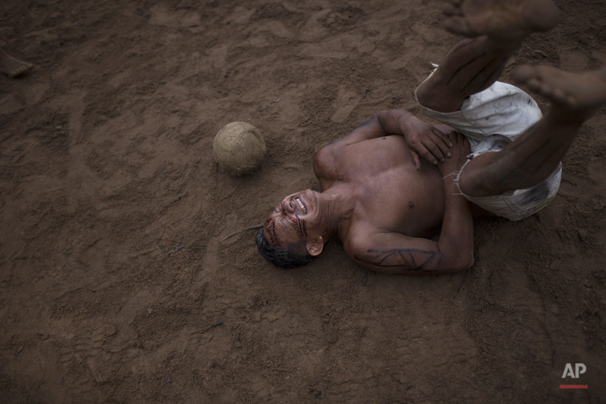  In this May 24, 2014, photo, a man reacts after being hit by the ball during a soccer game in the Tatuyo indigenous community near Manaus, Brazil. Manaus is one of the host cities for the 2014 World Cup in Brazil. (AP Photo/Felipe Dana) 