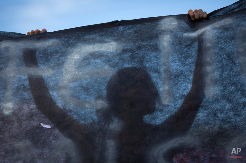  A woman holds up a black banner as people protest near the Kiss nightclub where a fire killed over 230 people in Santa Maria, Brazil, Tuesday, Jan. 29, 2013. The Rio Grande do Sul state forensics department raised the death toll Tuesday from 231 to 