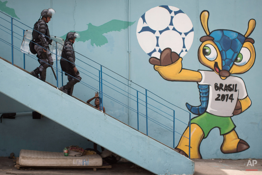  Riot police walk next to a mural of the mascot for the 2014 World Cup soccer tournament, called Fuleco, near the Maracana stadium, after evicting Indians from the nearby old Indian Museum in Rio de Janeiro, Friday, March 22, 2013. Police in riot gea