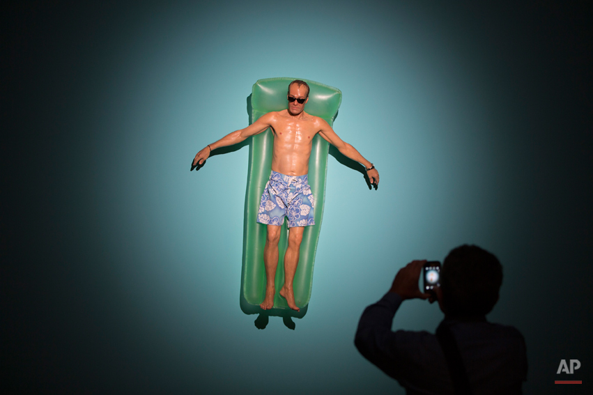  A visitor photographs a sculpture entitled 'Drift' by Australian artist Ron Mueck during the opening day of his exhibition at the Museum of Modern Art in Rio de Janeiro, Brazil, Wednesday, March 19, 2014. The exhibition will run from today to June 1
