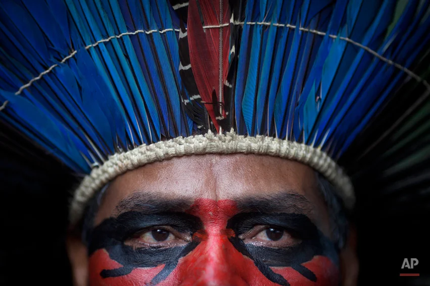 An indigenous man wearing face paint and a headdress stands inside the abandoned old Indian museum in Rio de Janeiro, Brazil, Thursday, March 21, 2013. Brazilian Federal Court ruled that indigenous people who have been occupying the building since 2006 have to leave the area because it is next to the Maracana stadium, which will be the site of the final match of the 2014 World Cup soccer tournament and the opening and closing ceremonies of the 2016 Olympic games. Authorities say the compound must go as the area around the stadium is being transformed into a shopping and sports entertainment hub. (AP Photo/Felipe Dana)
