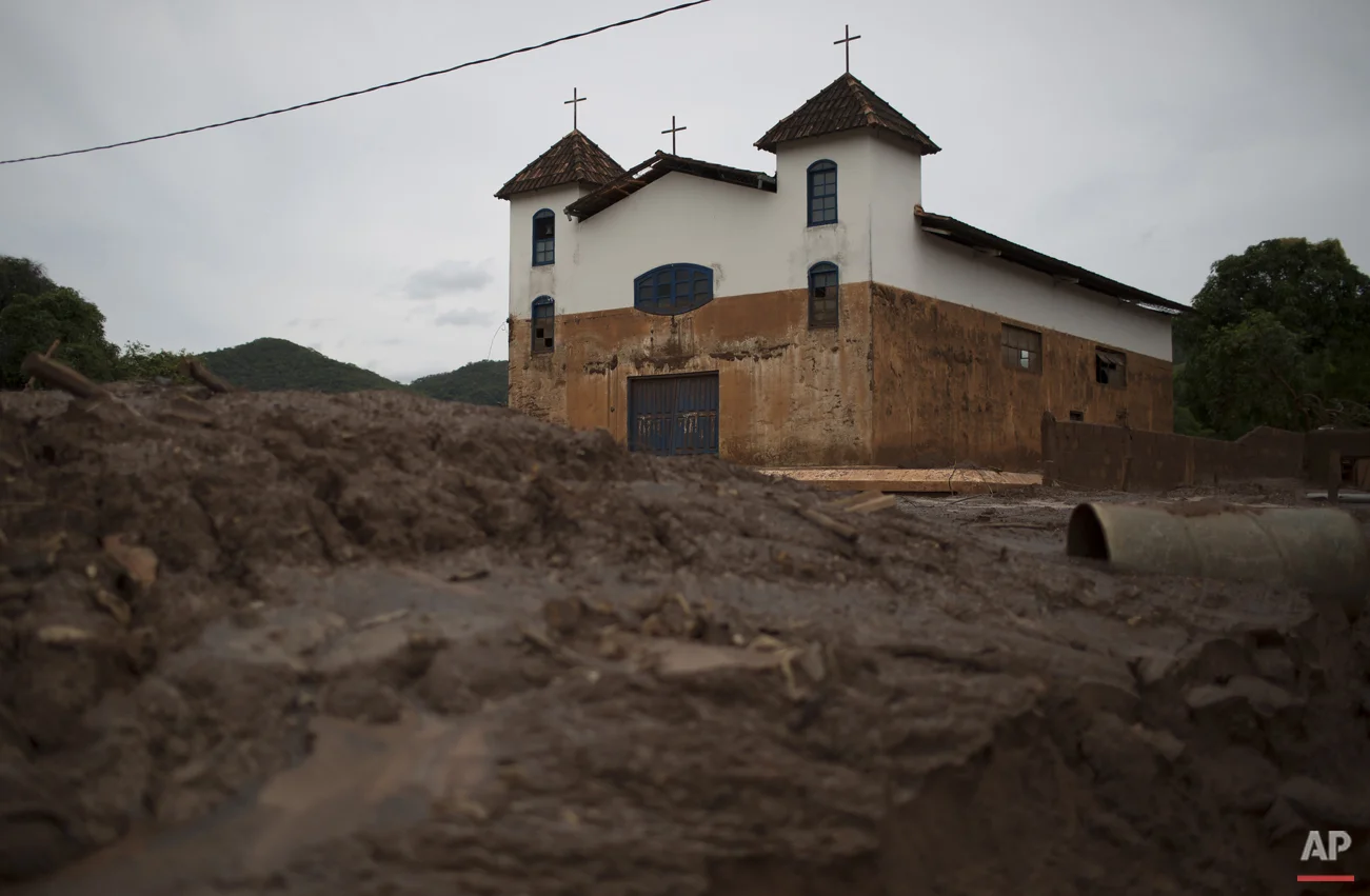 In this Nov. 24, 2015 photo, the color brown on the church's white walls indicate the level which water and mud reached during a recent mudslide triggered by the failing of a dam at a nearby iron ore mine, in Paracatu, Brazil. After the disaster hit, the hamlet of Paracatu and other nearby hamlets like Bento Rodrigues became ghost towns. (AP Photo/Leo Correa)