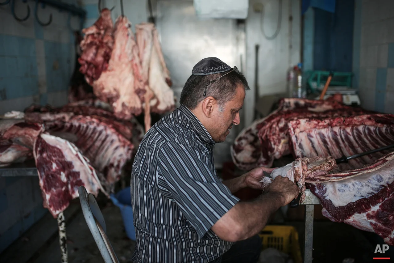 In this Wednesday, Oct. 28, 2015 photo, Char Haddad, 45, prepares meat in his kosher slaughterhouse at Hara Kbira, the main Jewish neighbourhood on the Island of Djerba, southern Tunisia. The surrounding streets include a kosher butcher, a bakery that sells a traditional tuna-filled pastry known as “brik” and schools that teach lessons in Hebrew, French and Arabic. (AP Photo/Mosa'ab Elshamy)
