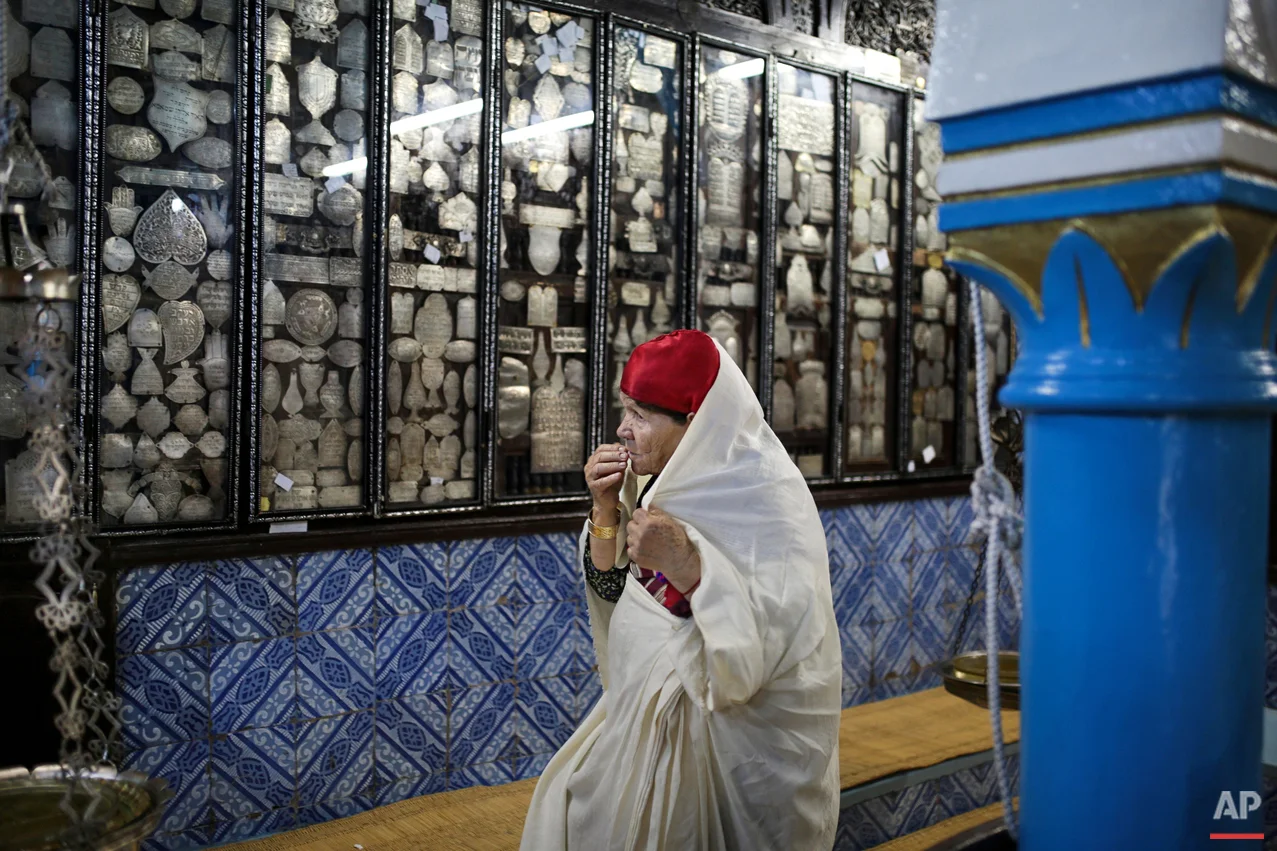 In this Wednesday, Oct. 28, 2015 photo, a Tunisian Jewish woman prays in La Ghriba, the oldest synagogue in Africa, on the Island of Djerba, southern Tunisia. The Jewish community in the resort island of Djerba traces its roots all the way back to Babylonian exile of 586 B.C., and is one of the few communities of its kind to have survived the turmoil around the creation of Israel, when more than 800,000 Jews across the Arab world either emigrated or were driven from their homes. (AP Photo/Mosa'ab Elshamy)