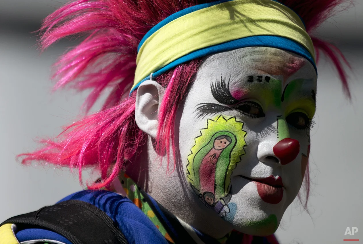 A clown with his cheek painted with an image of the Virgin of Guadalupe walks in a procession toward the Basilica of Our Lady of Guadalupe in Mexico City, Monday, Dec. 14, 2015. Hundreds of clowns belonging to various clown associations made their annual pilgrimage to the Basilica on Monday to pay their respects to the Virgin of Guadalupe, Mexico's patron saint. (AP Photo/Rebecca Blackwell)