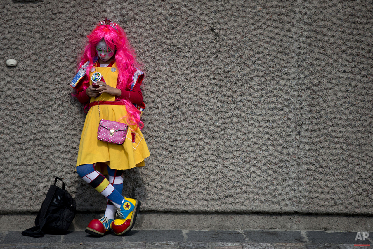 A clown checks her phone as she waits outside the Basilica of Our Lady of Guadalupe, in Mexico City, Monday, Dec. 14, 2015. Hundreds of clowns belonging to various clown associations made their annual pilgrimage to the Basilica on Monday to pay their respects to the Virgin of Guadalupe, Mexico's patron saint. (AP Photo/Rebecca Blackwell)