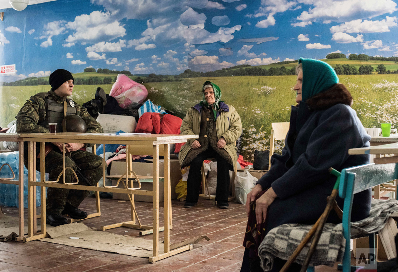 A Ukrainian soldier, left, sits next to two elderly women waiting for humanitarian aid in Avdiivka, eastern Ukraine, Sunday, Feb. 5, 2017. A sharp escalation in fighting between Ukrainian troops and Russia-backed rebels over the past week has killed at least 33 people, centering on Avdiivka, a government-held town just north of rebel-controlled Donetsk. (AP Photo/Evgeniy Maloletka)