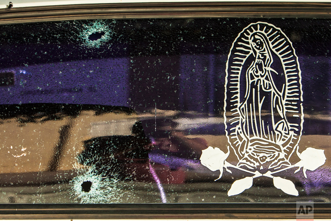 The rear windshield of a vehicle is held together by a transparent film with an image of the Virgin of Guadalupe, after being struck by bullets in Culiacan, Mexico, Tuesday, Feb. 7, 2017. The Sinaloa state prosecutor's office said in a statement that several suspects and a Mexican marine died in an early morning clash after heavily armed men attacked the marines while on patrol in the city. (AP Photo/Rashide Frias)