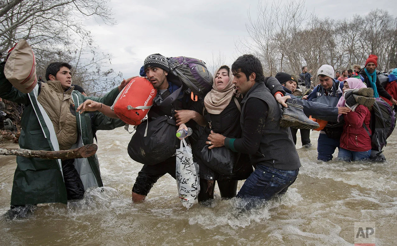 A woman is supported by two men while crossing a river as migrants attempt to reach Macedonia on a route that would bypass the border fence, Monday, March 14, 2016. Hundreds of migrants and refugees walked out of an overcrowded camp on the Greek-Macedonian border Monday, determined to use a dangerous crossing to head north. AP photographer Vadim Ghirda of Romania won second prize in the Contemporary Issues - Singles category in the 2017 World Press Photo competition with an emotionally charged photo of migrants crossing a river as they attempt to reach Macedonia. (AP Photo/Vadim Ghirda)