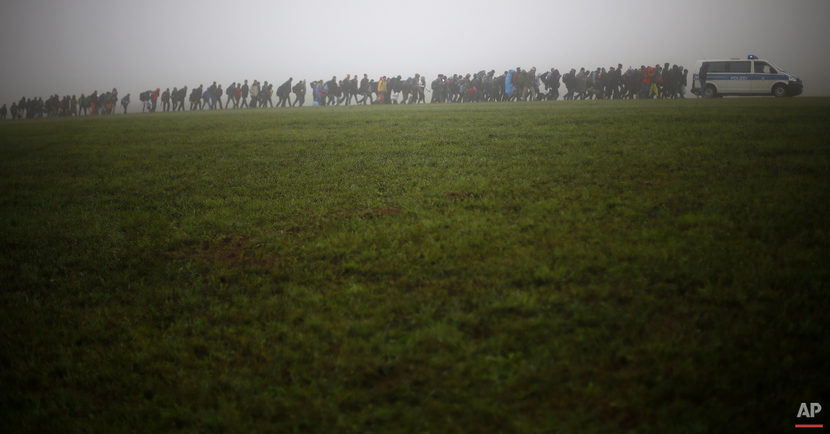  German federal police officers guide a group of migrants on their way after crossing the border between Austria and Germany in Wegscheid near Passau, Germany, Thursday, Oct. 15, 2015. (AP Photo/Matthias Schrader) 