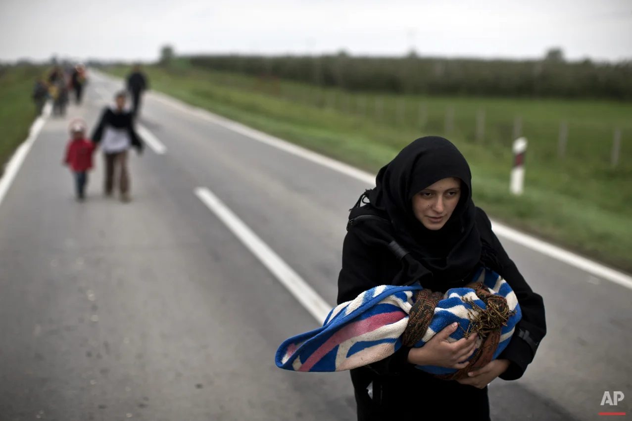 A woman carries a child as she moves on foot towards a registration center in Opatovac, Croatia, Tuesday, Oct. 20, 2015. (AP Photo/Marko Drobnjakovic)