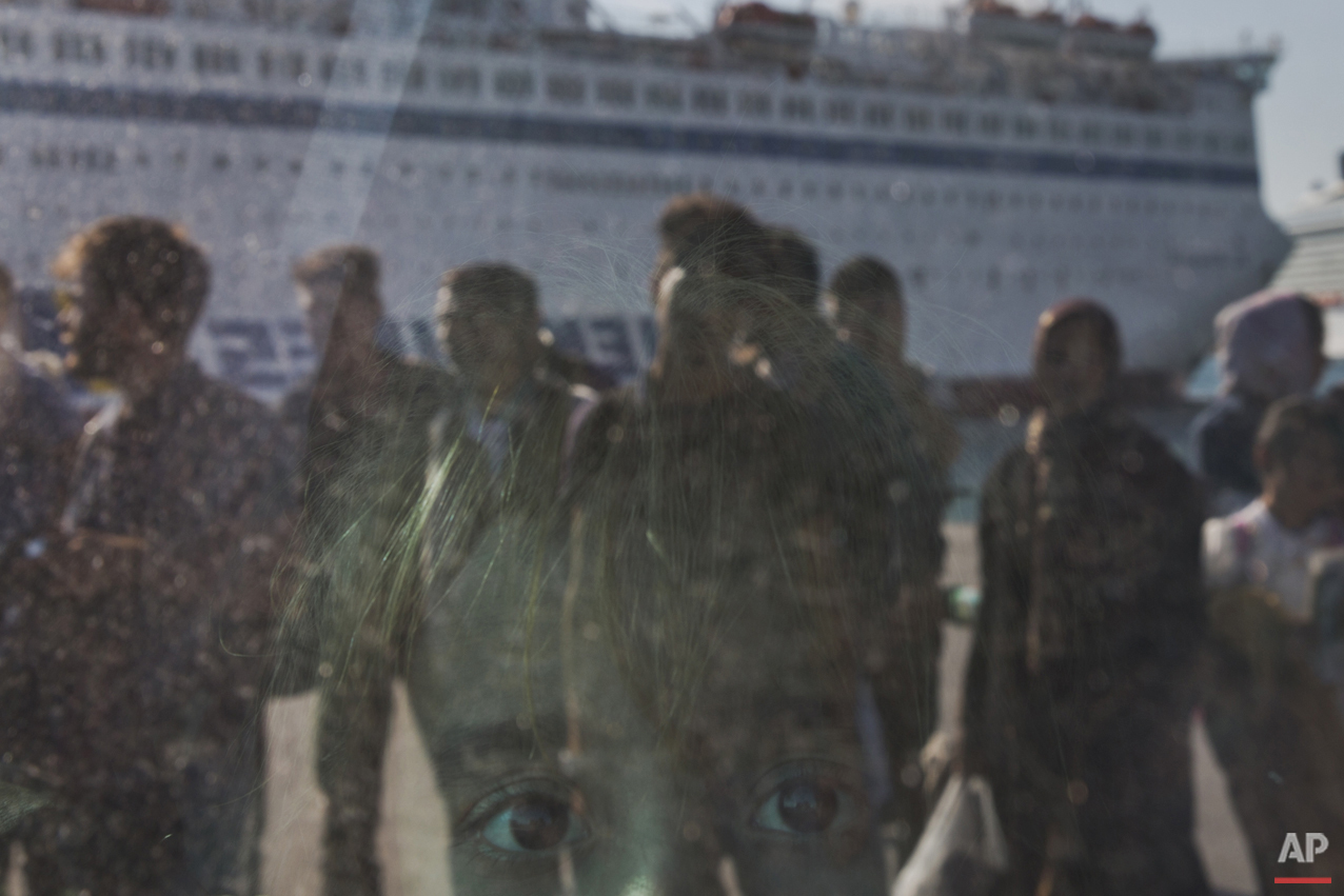 A child looks out from a window of a bus upon arriving by a ferry from the Greek island of Lesbos at the Athens' port of Piraeus on Thursday, Oct. 15, 2015. The international Organization for Migration said than more than 593,000 people have crossed