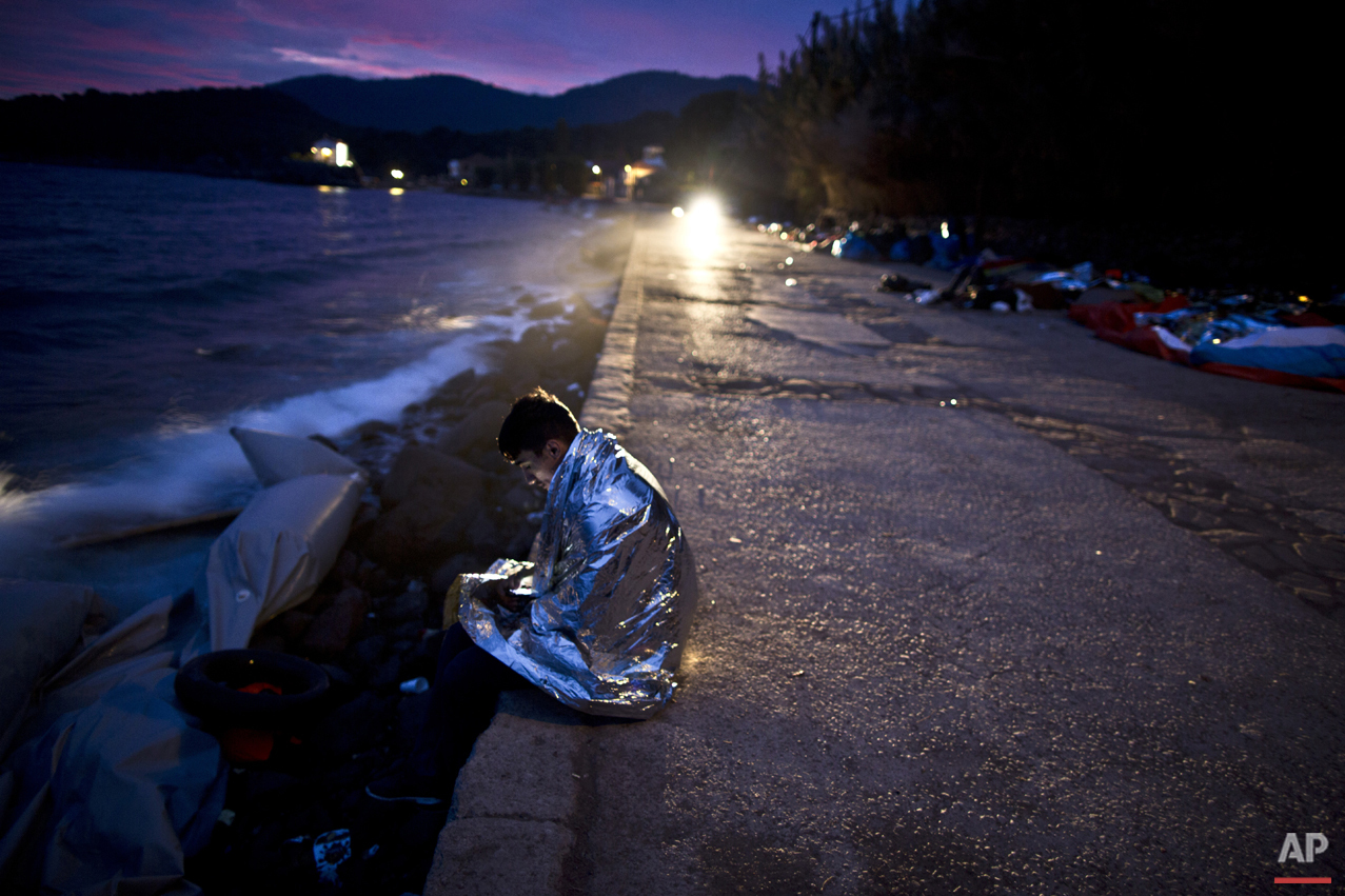  An Afghan refugee wrapped, in a thermal blanket faces the sea after he and others arrived late in the night on a dinghy from the Turkish coast to the northeastern Greek island of Lesbos, early Thursday, Oct. 8 , 2015. (AP Photo/Muhammed Muheisen) 