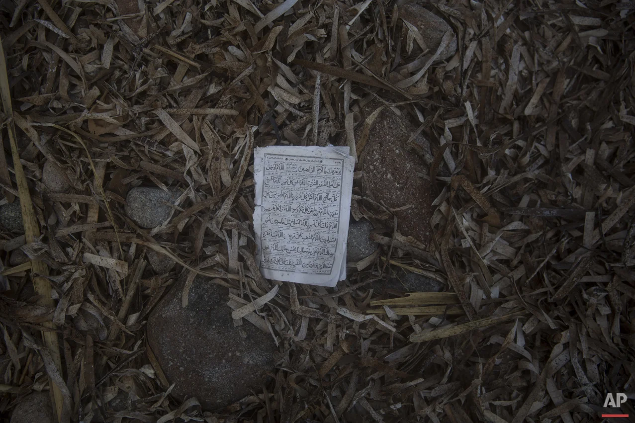 A page form the Quran lies on the beach in the Greek island of Lesbos, where hundreds of refugees are arriving every day from the Turkish coast, Friday, Oct. 2, 2015. (AP Photo/Santi Palacios)