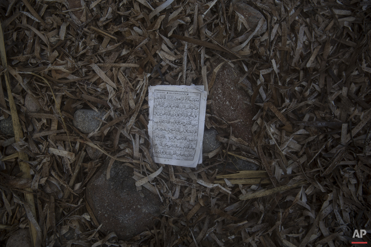  A page form the Quran lies on the beach in the Greek island of Lesbos, where hundreds of refugees are arriving every day from the Turkish coast, Friday, Oct. 2, 2015.  (AP Photo/Santi Palacios) 
