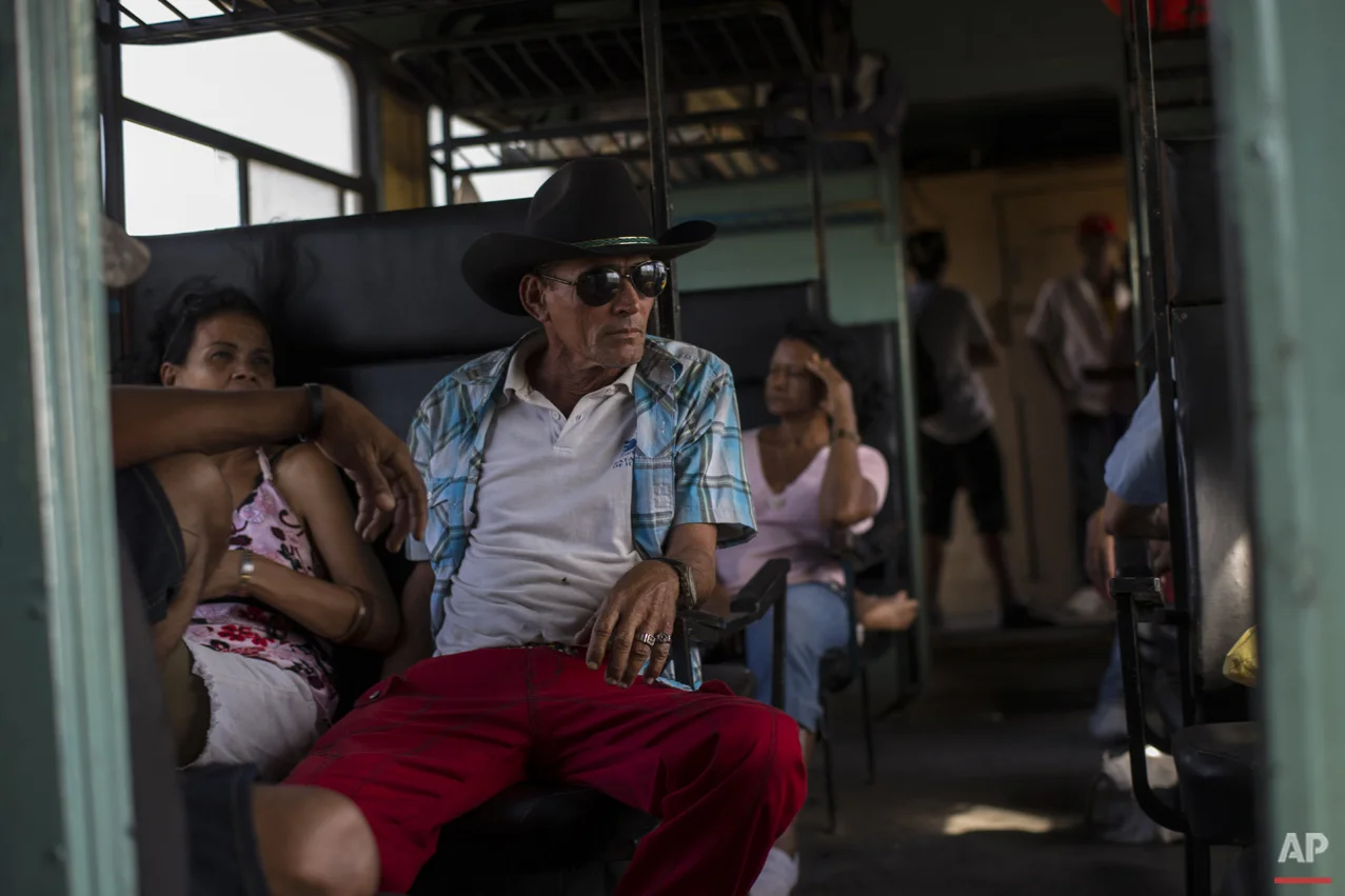 In this March 23, 2015 photo, a working cowboy travels by train to Santa Clara to participate in a rodeo, as the train moves through the province of Holguin, Cuba. From east to the west, trains offer a fine-grained, slow-moving view of Cuba that few foreigners ever see. (AP Photo/Ramon Espinosa)