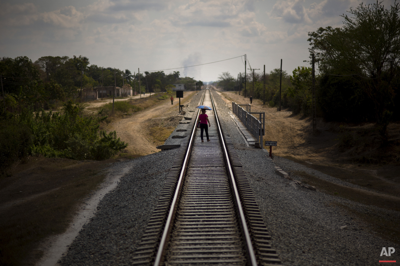  In this March 23, 2015 photo, a woman who just got off the train uses the tracks to cross a bridge after arriving to her destination in the province of Holguin, Cuba. Cuba became the first Latin American country with a train system in the mid-19th c