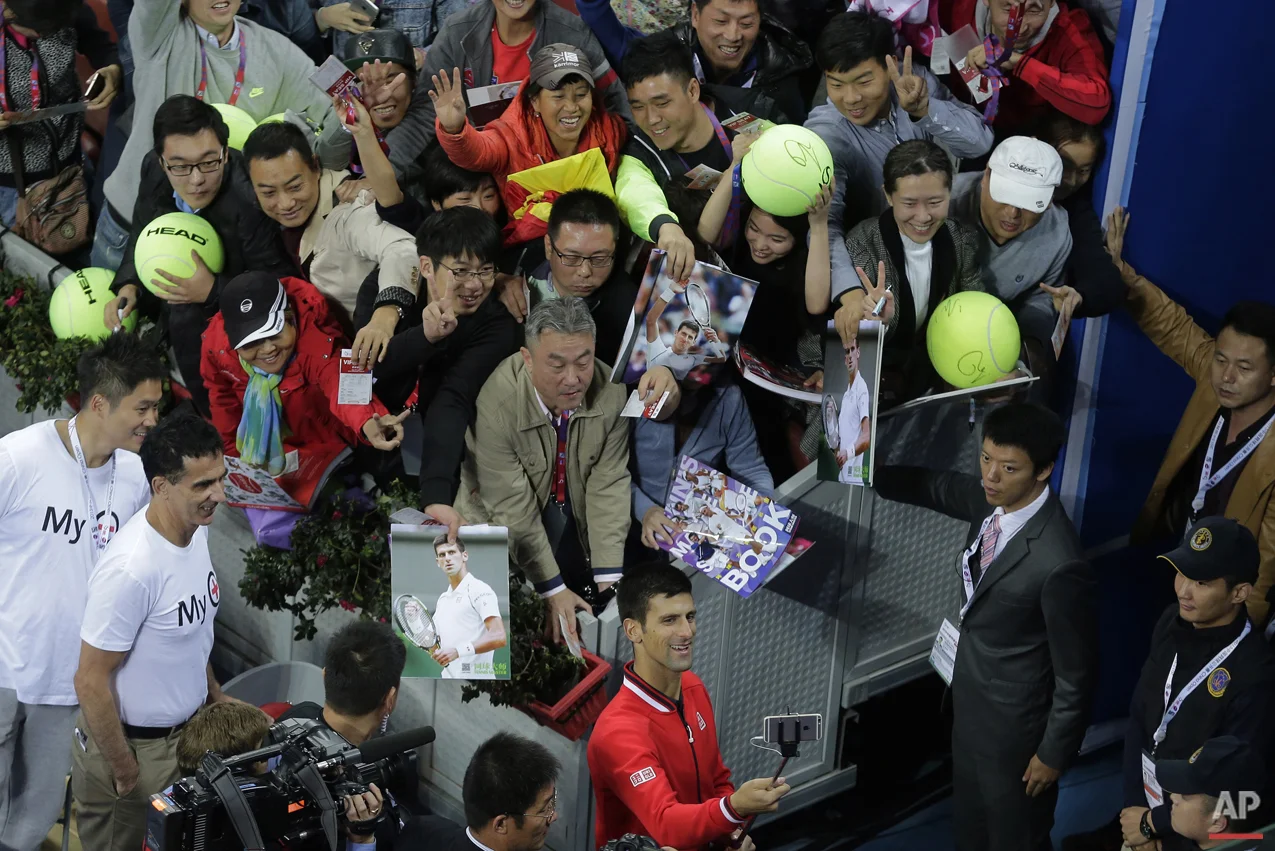 Novak Djokovic of Serbia, bottom, takes a selfie with spectators after winning his men's singles final match against Rafael Nadal of Spain in the China Open tennis tournament at the National Tennis Stadium in Beijing, Sunday, Oct. 11, 2015. (AP Photo/Andy Wong)