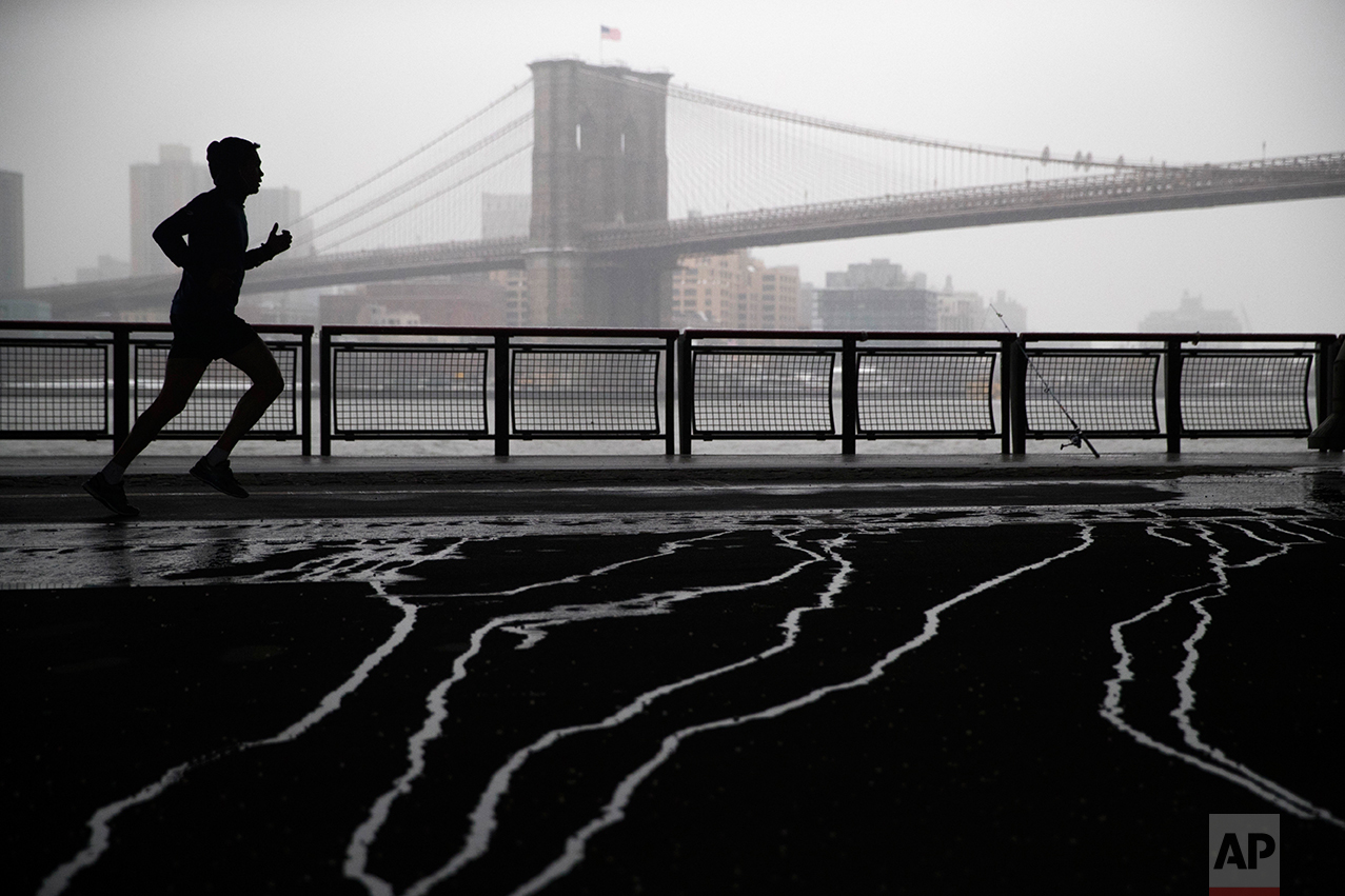  Snow falls as a jogger, framed by the Brooklyn Bridge, runs underneath the Franklin Delano Roosevelt Drive overpass, Tuesday, Jan. 31, 2017, in lower Manhattan. (AP Photo/Mary Altaffer) 