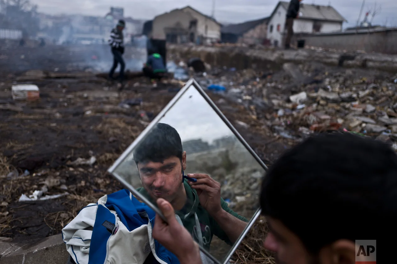 In this Thursday, Feb. 2, 2017 photo, unaccompanied minor Tasawor, 17, a migrant from Afghanistan, shaves outside an abandoned warehouse where he and other migrants took refuge in Belgrade, Serbia. (AP Photo/Muhammed Muheisen)