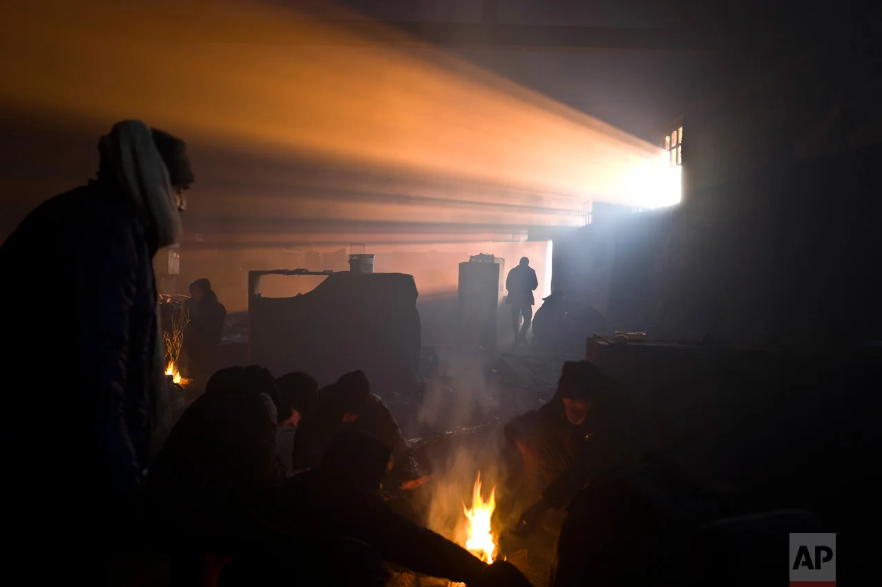 In this Monday, Jan. 30, 2017 photo, migrants including unaccompanied minors shield from the cold around fires in an abandoned warehouse where they took refuge in Belgrade, Serbia. (AP Photo/Muhammed Muheisen)