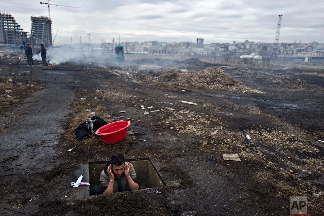 In this Thursday, Feb. 2, 2017 photo, unaccompanied minor Ehsanullah, 14, a migrant from Jalalabad, Afghanistan, washes himself in a hole in the ground outside an old train carriage where he and other migrants took refuge in Belgrade, Serbia. (AP Photo/Muhammed Muheisen)