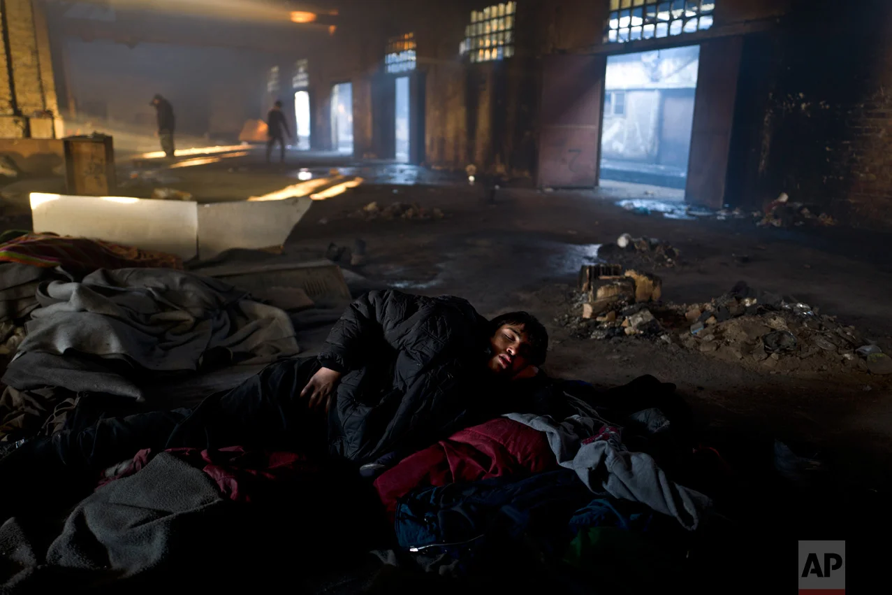 In this Saturday, Feb. 4, 2017 photo, unaccompanied minor Obaidullah, 14, a migrant from Wardak, Afghanistan, sleeps on the ground of an abandoned warehouse where he and other migrants took refuge in Belgrade, Serbia. (AP Photo/Muhammed Muheisen)