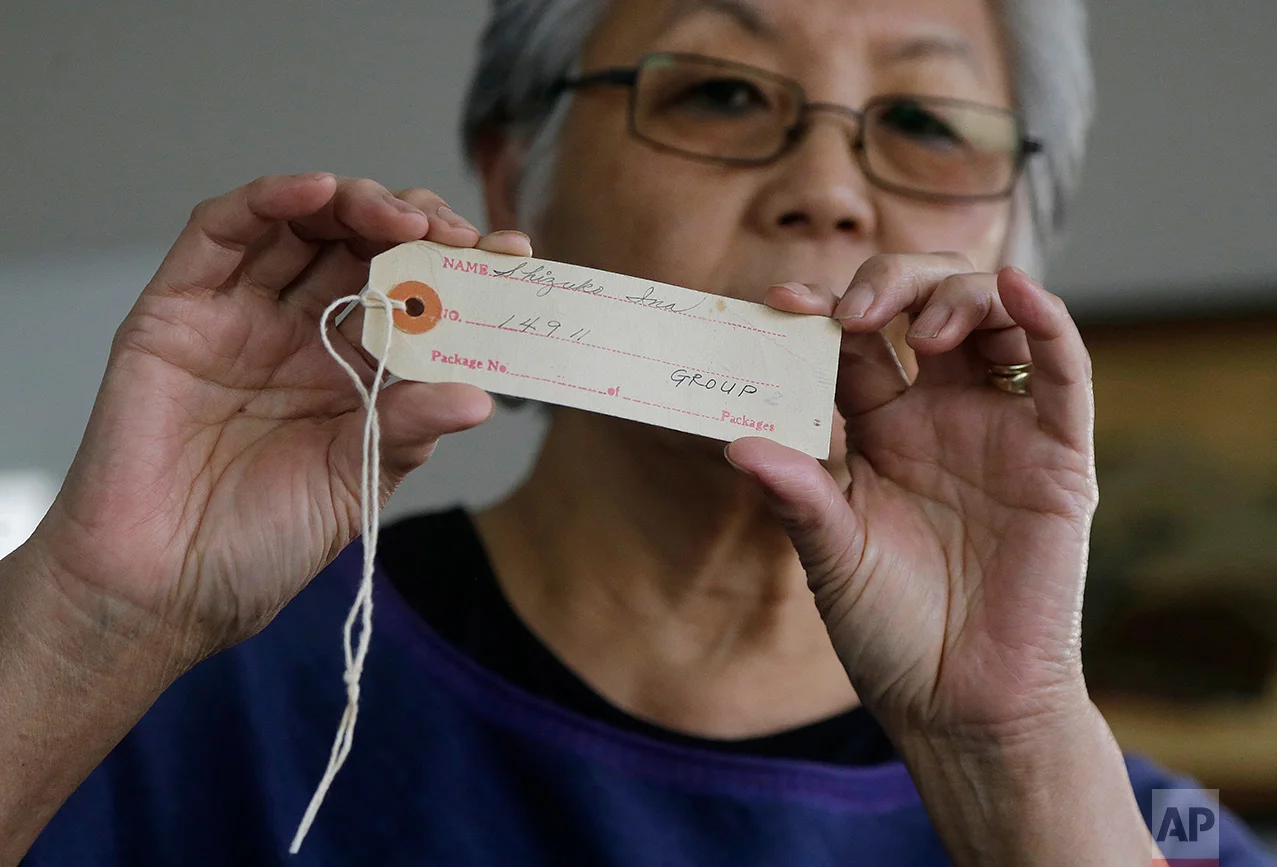 In this Feb. 10, 2017 photo, Satsuki Ina holds up an identification tag issued to her mother, Shizuko Ina, at her home in Oakland, Calif. As Japanese Americans mark the 75th anniversary of the executive order that authorized their incarceration, they're speaking out against new presidential orders that limit travel and target immigrants. (AP Photo/Jeff Chiu)