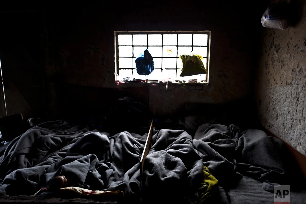 In this Tuesday, Feb. 7, 2017 photo, unaccompanied minors, right, sleep on the ground with older ones in an abandoned warehouse where they took refuge in Belgrade, Serbia. (AP Photo/Muhammed Muheisen)