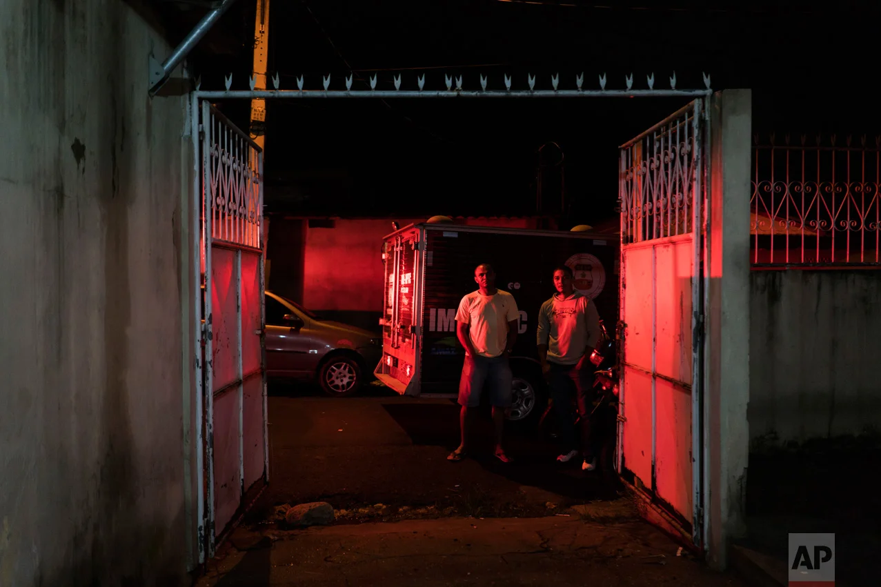 In this Feb. 5, 2017 photo, residents watch police inspect a home where a woman was shot to death in Manaus, Brazil. "Citizens are the ones who are truly jailed these days," said Claudio Lamachia, head of Brazil's bar association. "Members of the crime gangs are dictating the rules and stopping people from leaving their homes." (AP Photo/Felipe Dana)