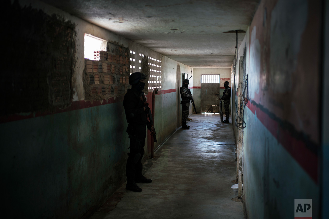 In this Feb. 2, 2017 photo, guards stand outside prison cells at the Monte Cristo agricultural penitentiary in Boa Vista, Brazil. Guards, administrative prison staff and families of inmates of this prison said gang leaders ordered newcomers to join killing sprees in January and dismember and behead the dead. (AP Photo/Felipe Dana)