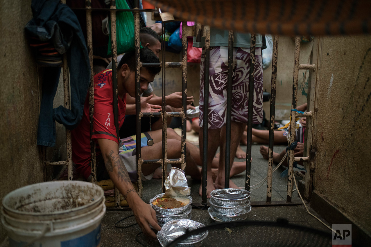 In this Feb. 6, 2017 photo, an inmate reaches for a plate of food during lunchtime inside an overcrowded cell at a police station near Manaus, Brazil. The business strategy of Brazilian crime gangs is to dominate overcrowded prisons, then control the streets. (AP Photo/Felipe Dana)In this Feb. 6, 2017 photo, an inmate reaches for a plate of food during lunchtime inside an overcrowded cell at a police station near Manaus, Brazil. The business strategy of Brazilian crime gangs is to dominate overcrowded prisons, then control the streets. (AP Photo/Felipe Dana)