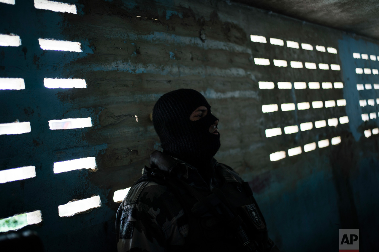 In this Feb. 2, 2017 photo, a masked guard stands outside prison cells inside the Monte Cristo Agricultural Penitentiary in Boa Vista, Brazil. "No one deserves to be here," a Venezuelan inmate here said through a small hole on the cell door. "Not the good people, not the bad, not anyone." (AP Photo/Felipe Dana)